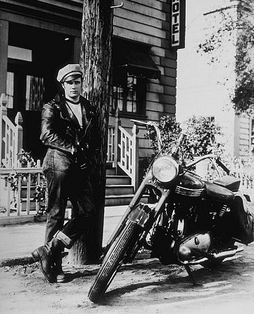 Marlon Brando standing in front of motorcycle.