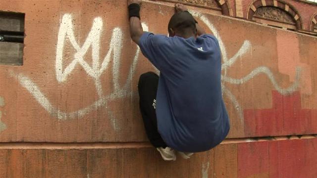 man dangling side of building graffiti 