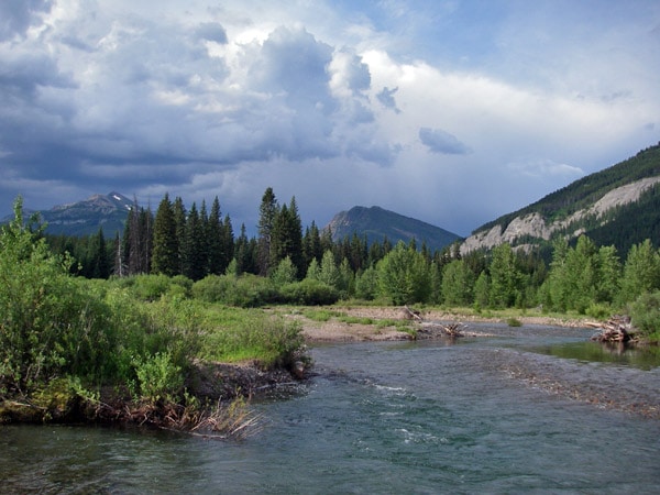 River flowing between the mountains in dark cloudy valley. 