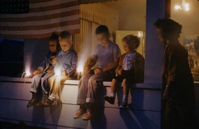 Vintage kids with sparklers in their hands sitting in the porch.