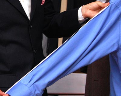 Tailor measuring the arm sleeve of blue dress shirt.