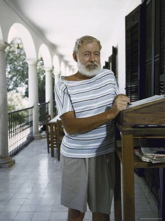 Ernest Hemingway standing with desk in the balcony.