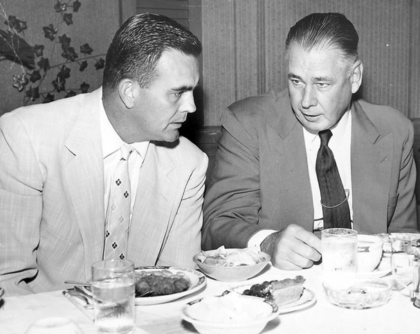 Vintage men in suits eating dinner at table.