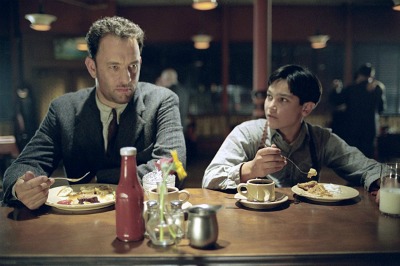 Tom Hanks and a boy eating in a Road to perdition movie.