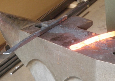 A red hot iron placed on an anvil for peining.