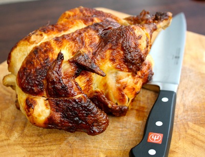 Rotisserie chicken and chef knife placed on the board.