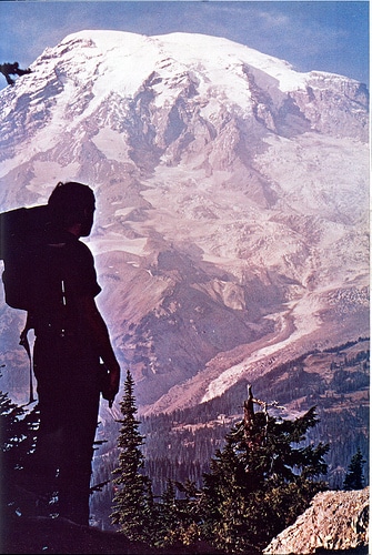 Man with backpacking silhouette on huge mountain.