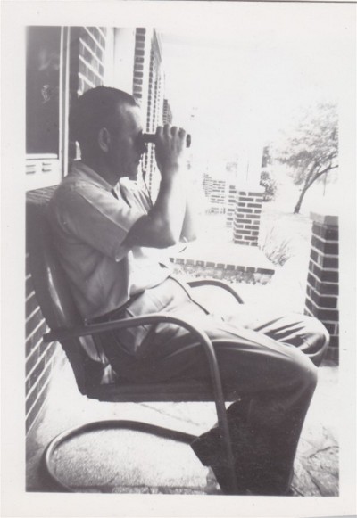 Man sitting on the chair looking through binoculars.