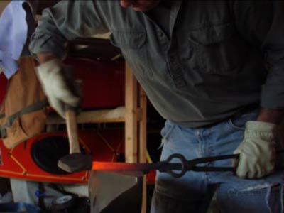 A man hammering hot iron to shape. 