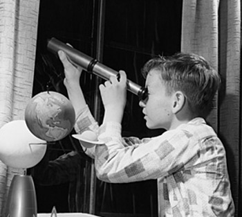 Vintage young boy looking out from the window with telescope.