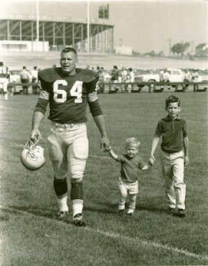 Vintage football player walking off the field with kids.