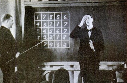 Vintage teacher memorizing the numbers to the student written on blackboard.