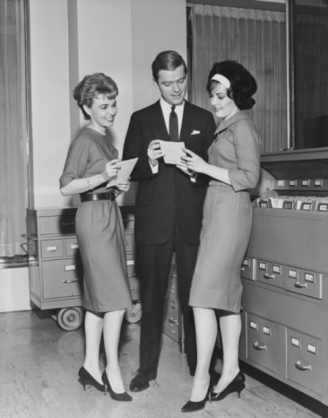 Vintage man speaking to women in office.