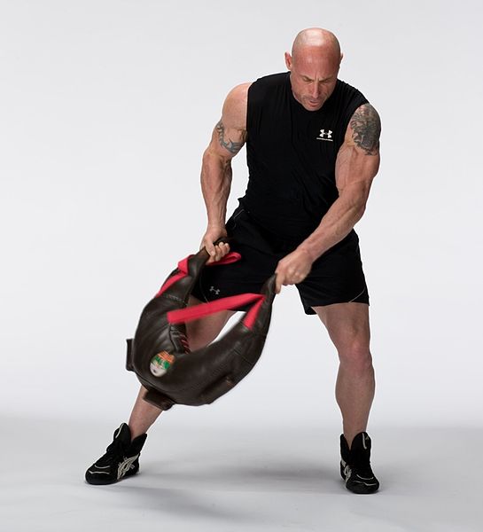 Strong man practicing with training bag.