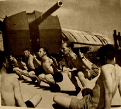 Vintage soldiers doing squats in front of tank ship.