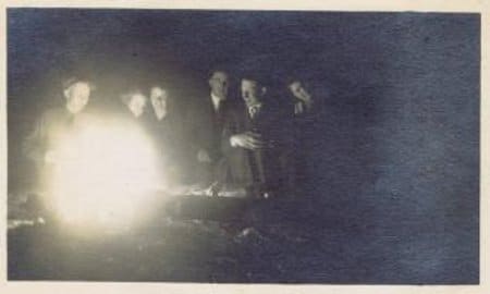 Vintage men sitting around campfire.