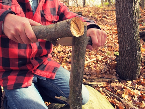 large survival knife splitting a small log 