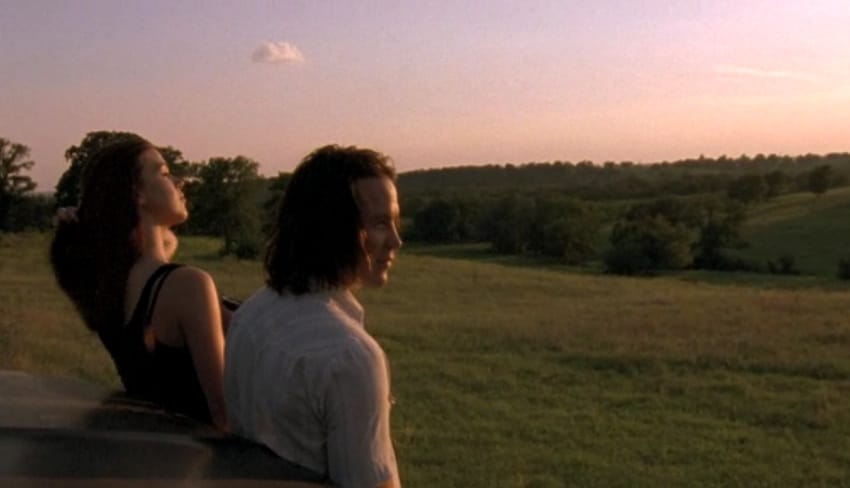 Tim Riggins looking over field and sunset view with girl.