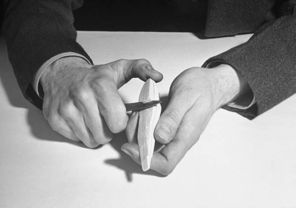 Vintage man whittling a wood with knife.