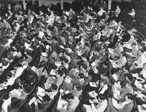 Vintage classroom full of students taking notes.