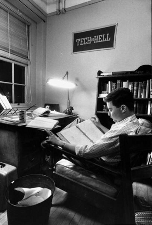 Vintage man studying in dorm room at desk in chair.