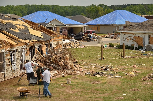 Homes wrecked and destroyed by tornado and men working to fix it.