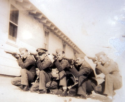 Vintage soldiers kneeling and aiming guns at unseen target.