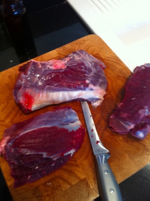 Cutting off the pieces of deer meat with knife.