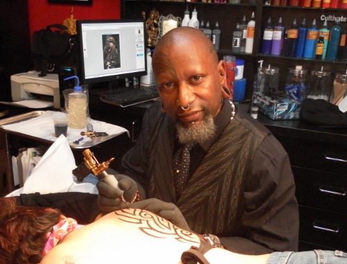  Zulu making tattoo on man's back.