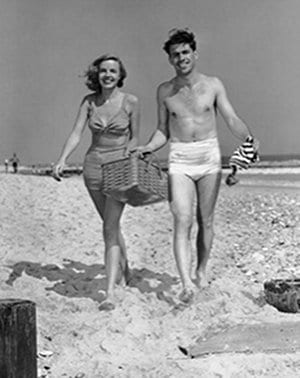 Vintage couple walking on beach for picnic. 