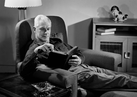 Vintage man sitting on chair and reading book. 