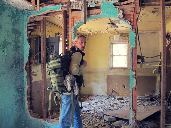 Man carrying backpack and visiting an old house.