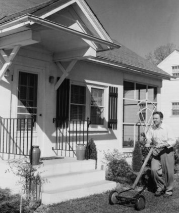 Vintage-Mann schiebt Spindelmäher vor einem Haus.