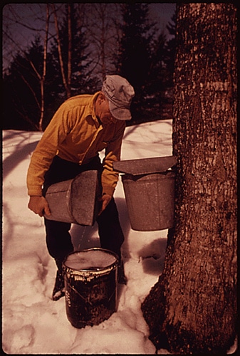 Man pouring water into bucket in cold weather.