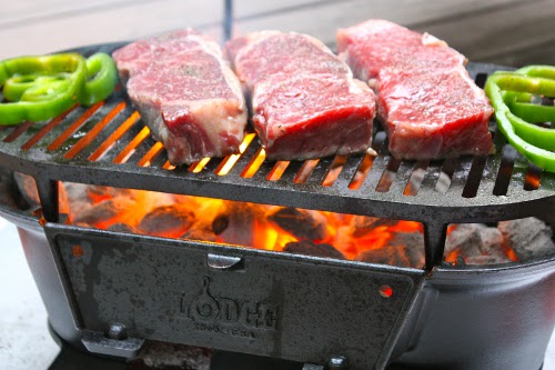 Cast iron grilled strip steaks raw meat green peppers.