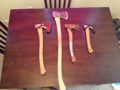 Assortment of axes on table with sheaths.