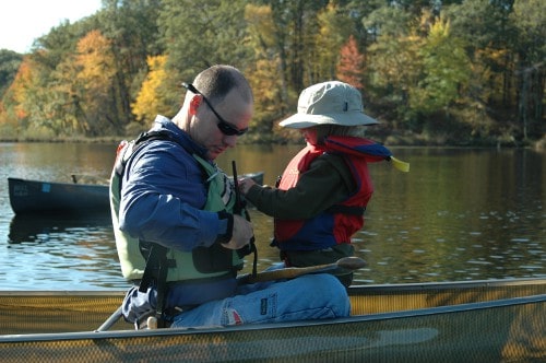 Man enjoying canoeing in lake with son.