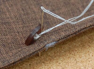 Needle passed through the cloth while sewing button.