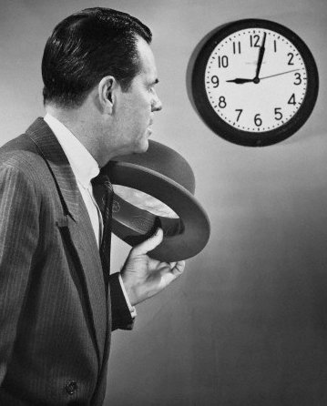 Vintage man businessman hat off looking at clock.