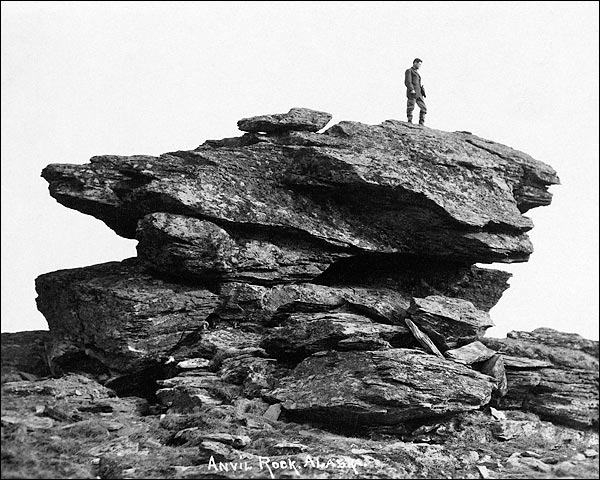 Vintage man standing on large anvil rock alaska.