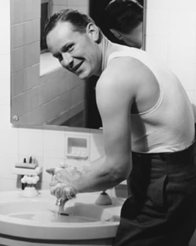 Vintage man washing hands wearing tank top.