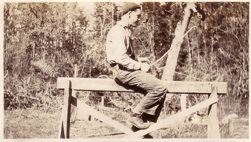Vintage young man sitting on wooden sawhorse.