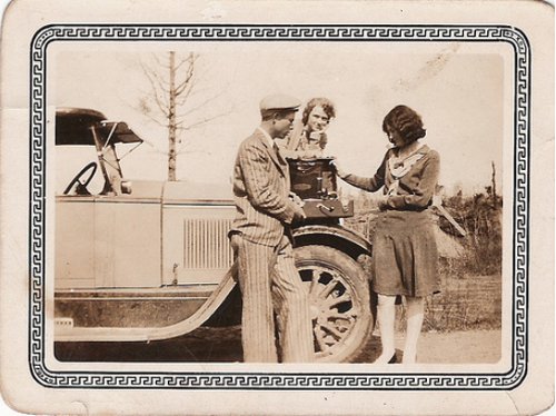 Vintage man selling vinyl record player on car hood.