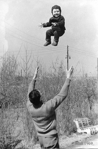 Vintage dad throwing son baby high into air.