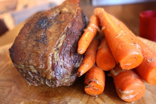 Roast beef and carrots cooked on cutting board. 