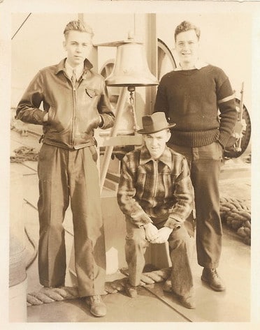 Vintage young men posing in front of bell. 