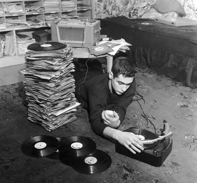 Young man lying on floor stack of records and vinyl player. 