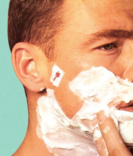 Vintage man face covered with shaving foam and toilet paper on face shaving cut. 