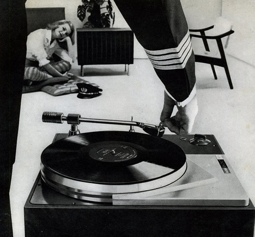 Women sitting on floor listing music a man in uniform hand was adjusting gramophone record.