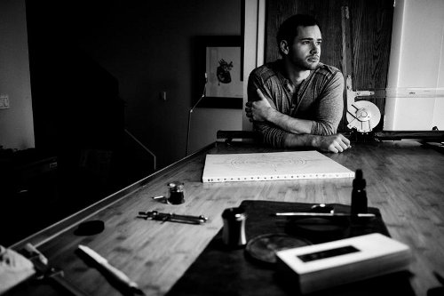 Master Penman Jake Weidmann at desk in black & white photo.